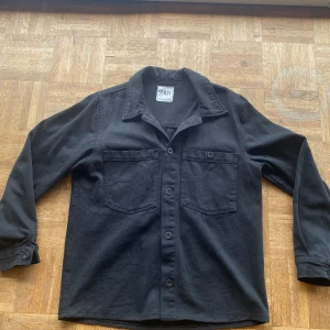Svart skjorta från Zara - En svart overshirt skjorta från Zara med långa ärmar och knappar framtill.