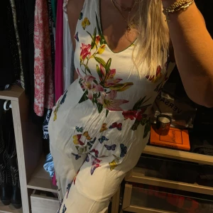 Jumpsuit med blommor - Lite kortare jumpsuit i vitt med blommor. Jättegullig!! Från Derhy, storlek M. Knytning och öppen rygg som är otroligt vacker! 