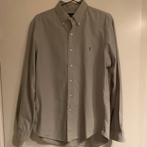 RALPH LAUREN SKJORTA - Ralph Lauren skjorta i bra skick. Använd ett få antal gånger. Skjortan ser grå ut men har också en lite mörkare ljusgrön nyans. Vid vidare funderingar tveka inte på att kontakta :) 