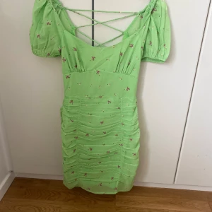 Klänning - En grön blommig sommarklänning med detaljer från NELLY.