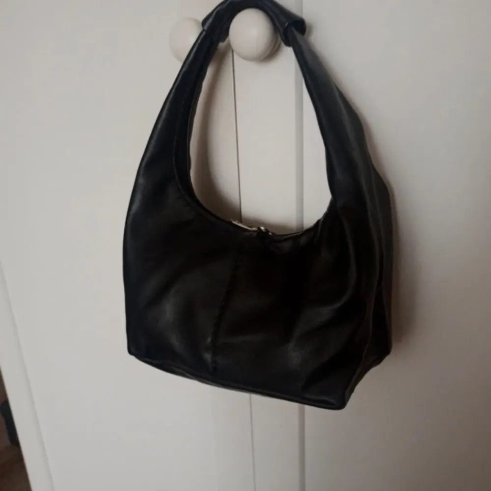 Säljer denna fina svart skinväska. Den är i fint skick och perfekt storlek! Ekologiskt läder. 25 cm x 15 cm. Väskor.