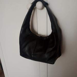 Säljer denna fina svart skinväska. Den är i fint skick och perfekt storlek! Ekologiskt läder. 25 cm x 15 cm