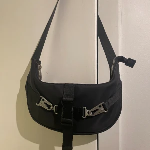 Axelväska 90-talsstil  - Axelväska från Asos design i 90-talsstil med metalldetaljer framtill. 1 innerfack i väskan. Sparsamt använd. 