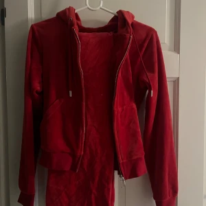 Juicy Couture set röd - Säljer ett rött juicy set i storlek M. Koftan är i fint skick, byxorna är lite mer slitna. Tycker att byxorna är en något ljusare färg än koftan. Säljes för 550kr som set. Annars 450kr för kofta och 100kr för byxorna.