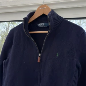 Ralph lauren zip  - Jätte snygg Ralph Lauren zip hoodie i fint skick utöver ett pytte hål i nacken inget som syns. Storlek L men sitter som en S. Modell runt 1,80. Dm för frågor