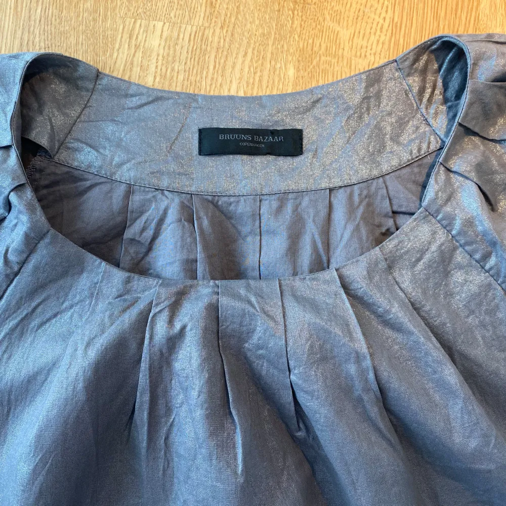 Plommonlila glittrig klänning från Bruuns Bazaar i strl 38.  Sparsamt använd och i fint begagnat skick.  Mått Över bröstet: ca 50 cm Längd från axeln och ner: ca 91 cm  100% bomull. Klänningar.