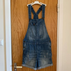 Blåa hängselshorts, strl S - Ett par hängselshorts från H&M för en ledig stil. De är normala i storleken och i hyfsat bra skick. Shortsen har använts ett par gånger och det finns två färgfläckar på dem. Se bilder. Från djur- och rökfritt hem. Frågor? Skicka ett dm!
