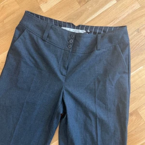 Kostymbyxor grå strl 44 - Jättefina kostymbyxor från Kappahl (äldre modell men verkar oanvända). Inköpta second hand. Så fina men säljer pga för stora. Inga fickor baktill.  Komposition 64% polyester, 31% viskos och 5% elastan, så de är väldigt sköna, lite stretchiga och anda