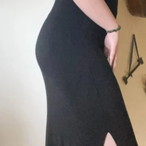 Svart långklänning med djup rygg och slits  - Skön klänning att dra på över bikinin i sommar men även till festligare tillfällen Superskönt material 