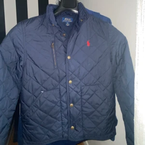 Ralph lauren Jacka - Ralph rauren jacka med knappar. Storlek M i barnstorlek, passar 10-12 år. Fint skick förutom ett litet hål vid ena fickan (sista bilden). Passar perfekt till Vår/ Höst, Hör gärna av er vid frågor!