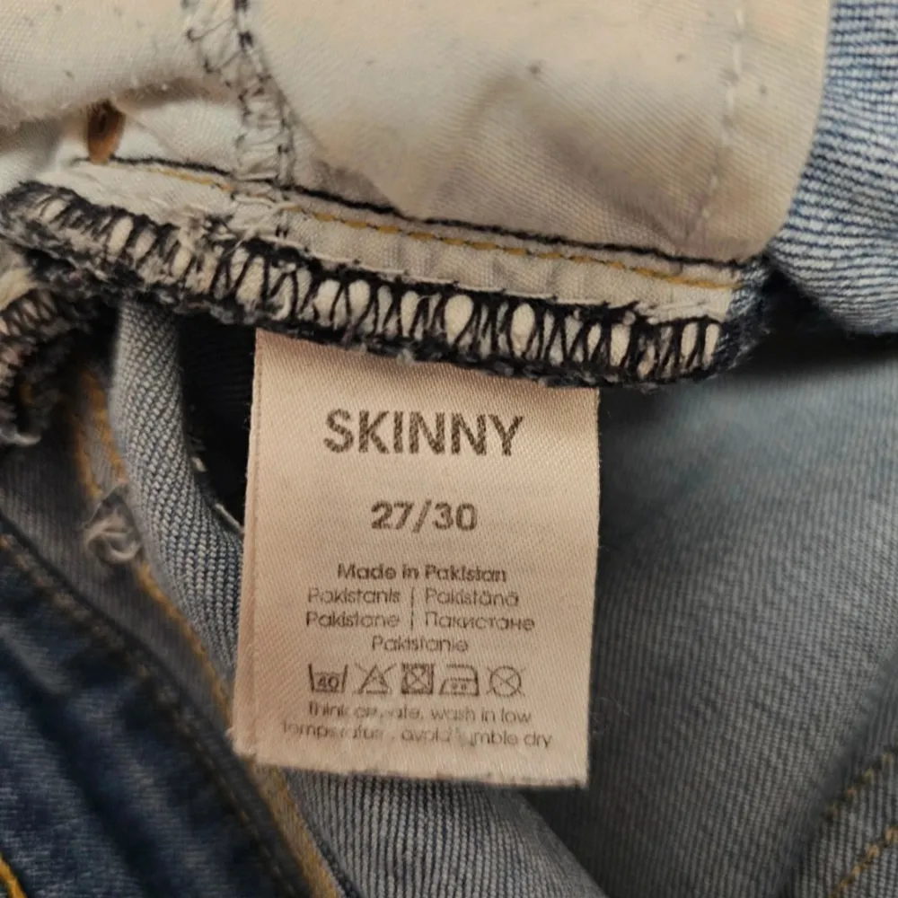 Ett par blå skinny jeans i storlek 27/30. Jeansen har en klassisk femficksdesign och är tillverkade i Pakistan. De har en knapp och dragkedja framtill.. Farkut & Housut.