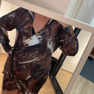 Klänning, lång top - Skön o stretchig klänning/lång top. Glansig o snyggt mönstrad. Djup urringning, knyt i sidan av midjan.  