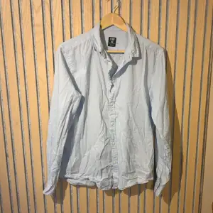 En ljusblå långärmad skjorta av lättare matrial för att kunna bli användbar på sommaren. Har endast användts fåtal gånger. Denna har inga hål eller andra slags defekter mycket bra skick. Kontakta mig vid frågor