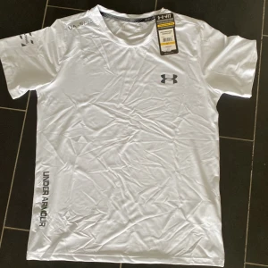 Under armour tröja - Vit under armour tröja, helt oanvänd och bra skick, perfekt till sommaren eller till gymmet.  Säljer då den för liten.