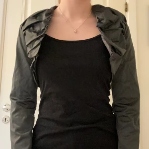 Bolero - Svart långärmad bolero som skimrar lite. 