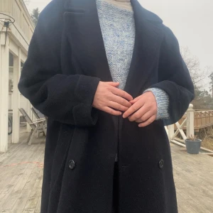 Mörkblå kappa  - Skön, mörkblå kappa som värmer under vintern. Står ej någon storlek men skulle gissa på L eller XL. På mig, som är 190cm lång sitter den oversize. Den är lite sönder vid ovansidan av slitsen på baksidan, inget som syns och går lätt att laga. 