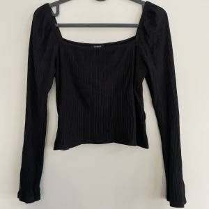 Svart ribbad topp från Lindex - Fin och skön topp i ribbat material från Lindex! Bra skick, endast använd ett par gånger. Den är något kort i modellen och har tyvärr blivit för kort i ärmarna på mig som är 178. Skriv gärna om du vill ha fler bilder eller har övriga funderingar!😊