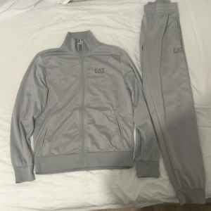 Emporio Armani EA7 grå tracksuit full set (kofta och mjukis) - Grå full set tracksuit, båda mjukisarna och koftan är i storlek Small (S), utmärkt skick bara använt runt 5 gånger, originalpris 1948,00 kr, mitt pris kan diskuteras!