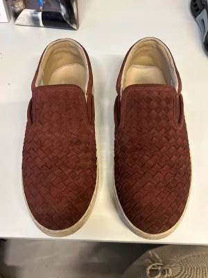 Bottega Veneta Sneakers - Bottega Veneta Nappa Intrecciato Suede Mens Slip On Sneakers 43 wine red! Dem eftertraktade Bottega slip onsen, kollektionen säljs inte längre och även färgen är extremt svår att hitta idag! Använda men fortfarande i fint skick! Nypris 8500