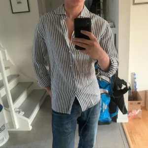 Linne skjorta från mango - Säljer denna somriga linneskjortan från mango i storlek XS. Blå och vitrandig. Hör av dig vid frågor eller funderingar!