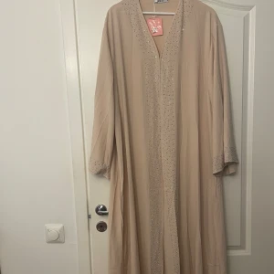 Abaya  - Helt ny och oanvänd abaya köpt utomlands, ljus rosa beige färg med silver kristall detaljer.