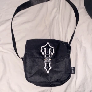 Trap star väska  - Det är en Trapstar väska för killar den är köpt 2023 knappt andvänd, säljer den för jag inte andvänder den och den är inte min stil 