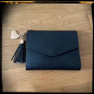 Plånbok svart med hänge  Aldrig använd Bredd 11 cm ihopfälld Höjd 8,5 cm Bredd 23,5 cm uppvikt