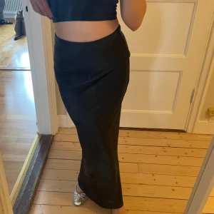 Lågmidjad maxikjol  - Svart satin lågmidjad maxikjol från Gina tricot i storlek xs. Helt oanvänd med lappen kvar. Passar xs-s då den är stretchig. 