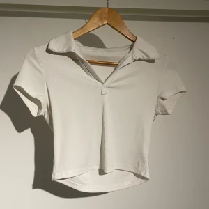 Vit magtröja  - En fin kortärmad magtröja! Använd fåtal gånger och i bra skick, plagget gånger bara lite konstigt på galejan