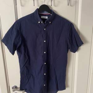 En Marinblå skjorta med korta ärmar från Jack & Jones i storleken xs. Den är använd 1-2 gånger så i super bra skick. Perfekt nu till sommaren.