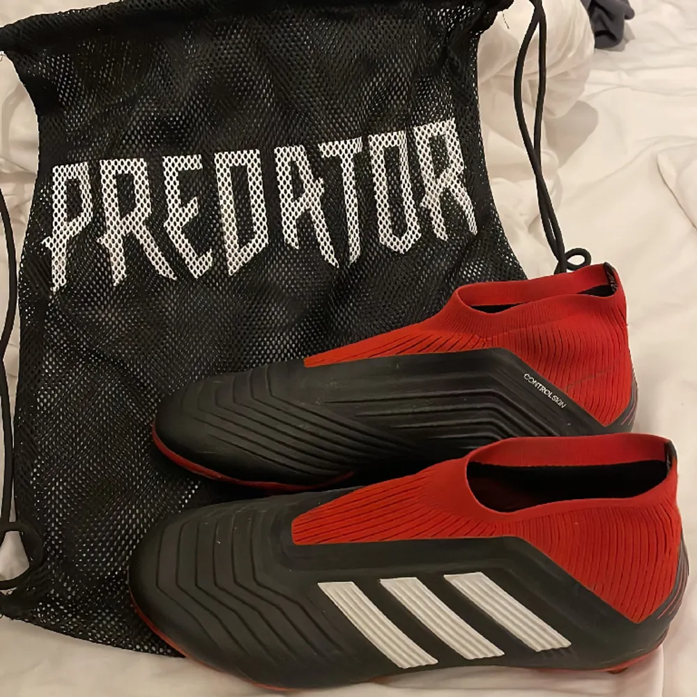 Adidas predator 18+ i färgen svart/röd. Sparsamt använda, lite smutsiga men annars felfria, storlek 38 2/3.. Skor.