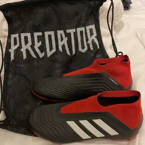 Adidas predator 18+ i färgen svart/röd. Sparsamt använda, lite smutsiga men annars felfria, storlek 38 2/3.