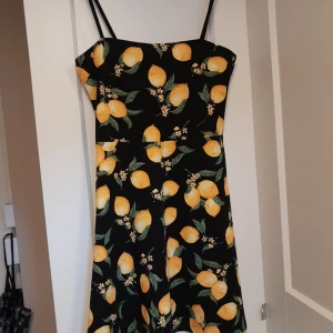 Citron klänning - Svart klänning med citroner på från H&M. Är i mycket bra skick, använd endast en gång då jag snabbt växte ur. Är mycket kort och även tight över bröstet på mig (S/M). Skulle säga att den är liten i storlek, typ XS ev. XXS