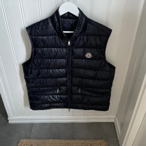 Moncler Gui Down väst mörklblå  - Äkta moncler väst med taggar och kvitto som är i 10/10 skick. Inga skador på den eller skavanker och har använts väldigt varsamt. Passar folk som är mellan 170-185! Riktigt skön väst att ha på sommaren. Pris diskuteras privat, nypris 8000 kr. 