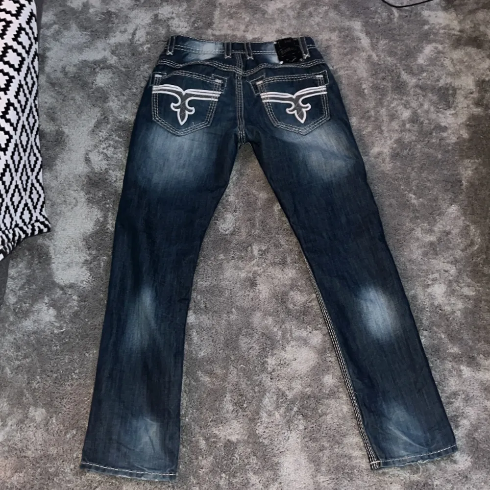 Tvär feta jeans med riktigt tuff fade, storlek W 33 L 32. Byxorna är ifrån rock revival å har massa tuffa detaljer. White stitch och feta knappar och mer. Byxorna är använda så har lite brister. Skriv för bilder på bristerna. . Jeans & Byxor.