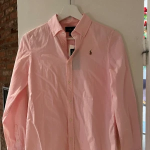 Rosa Ralph Lauren skjorta - Rosa Ralph Lauren skjorta storlek 14år/164. Passar även xs.  Lapparna kvar, endast provad. Hör av dig vid intresse.☺️