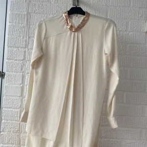 Vit lång tröja - Orginal pris 500 kr. Jag vill sälja denhära vita långa tröjan. Den har bara används 1 gång. Den är paljettig vid halsen. Det är en turkisk tröja. Och den har knappar vid handleden och vid nacken. Priset går att diskutera!