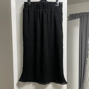 Midi skirt - Ginatricot - Midi skirt från Ginatricot i storlek M, svart färg med mönster. Fin och stretchig vid midjan. Köpt för 249kr säljer för 100kr.
