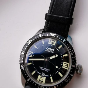 Oris Diver 65 40mm automatic - Oris Diver sixty-five black. Självlysande detaljer i urtavlan. Klockan behöver en service. Den funkar fint i övrigt. Box och cert finns tyvärr inte med. Ref nummer  01 733 7707 4064-07 4 20 18 Sapphire glas och jag har bytt spänne rem. Nypris 28.000: