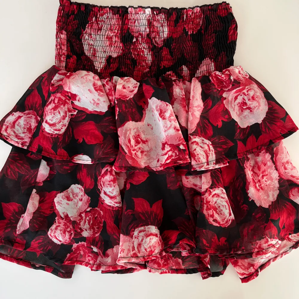 Röd/vit/svart kort kjol med volang i flera lager. Stretchig smock i midjan.   NA-KD Storlek XS, passar även S pga stretchig. 100% polyester. Kjolar.