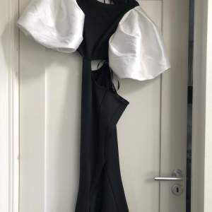 Dramatisk åtsittande svartvit klänning med cutouts, stora puffärmar och öppen rygg. Figursydd. Stl 36-38. Längd passar 157 cm m klackar.
