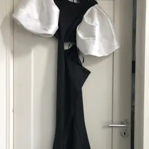 Dramatisk åtsittande svartvit klänning med cutouts, stora puffärmar och öppen rygg. Figursydd. Stl 36-38. Längd passar 157 cm m klackar.