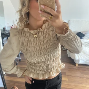 Blus - Superfin beige blus med volanger! Storlek S, passar också M pga att den är stretchig. Mycket bra skick! 