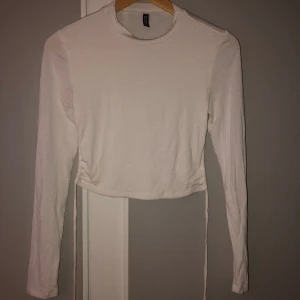 Topp med öppen rygg - Topp från H&M med öppen rygg, knytning där man kan dra åt och göra tröjan tajtare, kortare osv. Storlek S. Bara använd ett fåtal gånger.