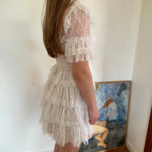 by malina studentklänning - vit spetsklänning med volang från by malina i modellen ”liona dress” i stl XS. lappen är kvar. klänningen är uppsydd för att bli en volang kortare men fortfarande nyskick. bestämde mig för en annan på studenten. andra bilden är lånad. nypris 2800 kr