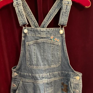 Hängselbyxor i jeans - Hängselbyxor i jeans, raka lite vida ben med slits nederst på benet, innerbenssöm: 69 cm, yttermått 100 cm, midja: 43 cm