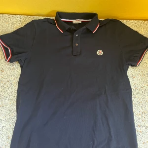 Mörkblå moncler polo  - Mörkblå moncler polo i storlek M.  Väldigt lite använd så den är i bra skick!!