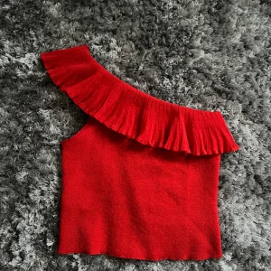 Röd one-sholder topp  - En jätte fin röd topp ifrån Mango som är använd en gång. Den är i storlek S och har fina volang detaljer. Toppen kan man styla snyggt med bara ett par jeans och är perfekt till vår/sommaren då rött är en trendig färg just nu🔥. Köpt för 349 kr. 
