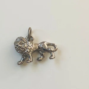 Berlock lejon  - Liten berlock föreställande lejon  Okänd metall 