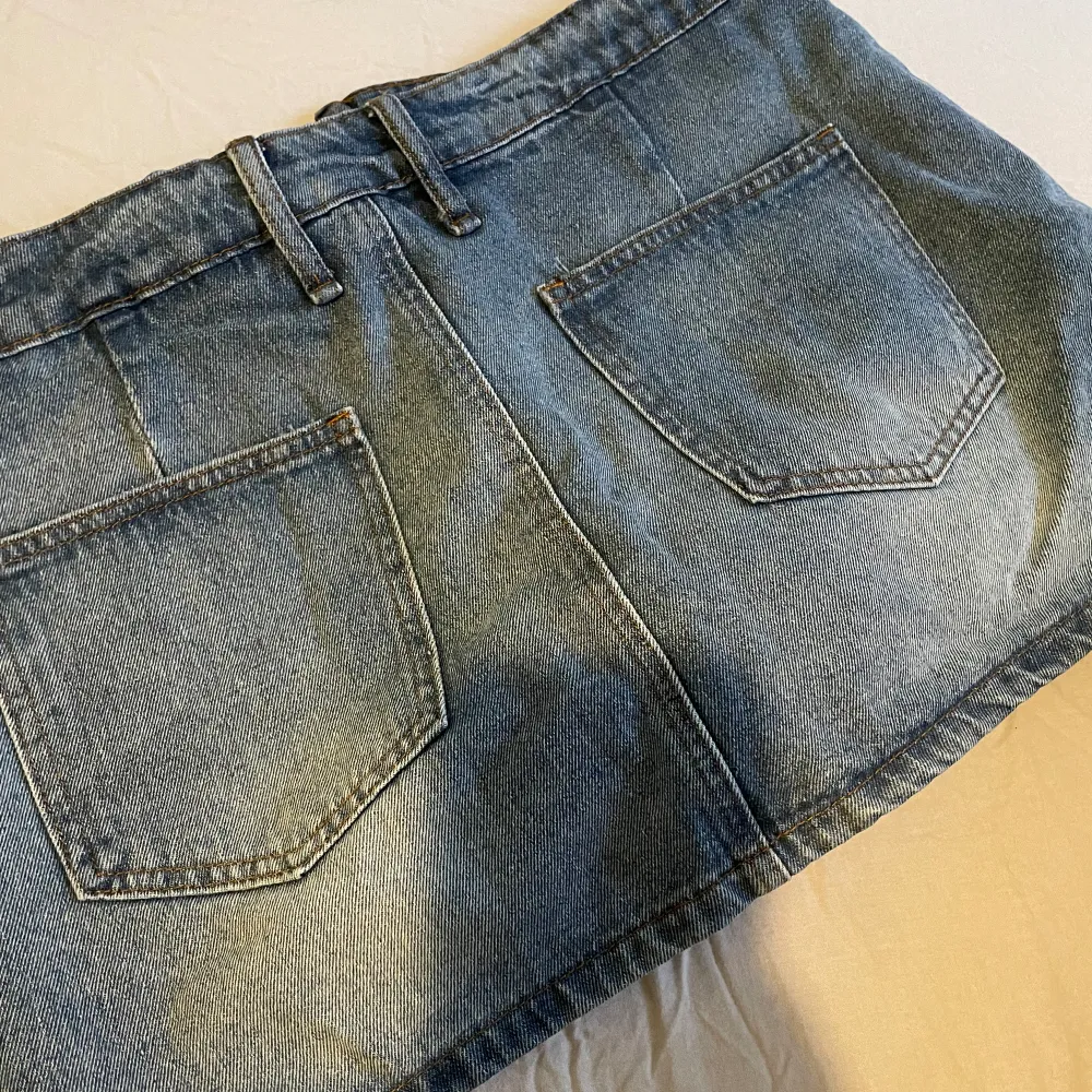 En kort jeanskjol med skärp. Säljs då den är för liten för mig.. Den är helt ny, aldrig använd. Det är stl L men är väldigt liten i stl, sitter som en S/M.  Den har bekväma och inbyggda shorts under så man inte råkar visa onönskade delar😊Nypris 229kr. Kjolar.